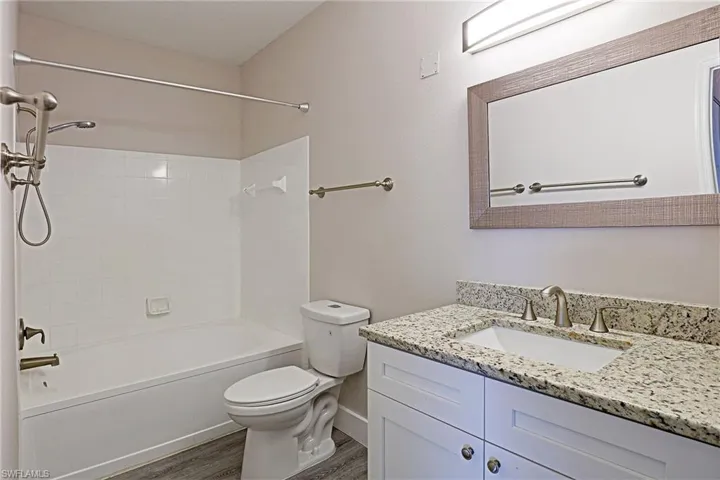 Full bathroom featuring vanity, tub / shower combination, and dark wood-type flooring