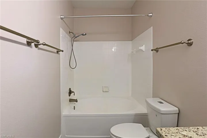 Bathroom featuring bathing tub / shower combination, vanity, and a textured wall