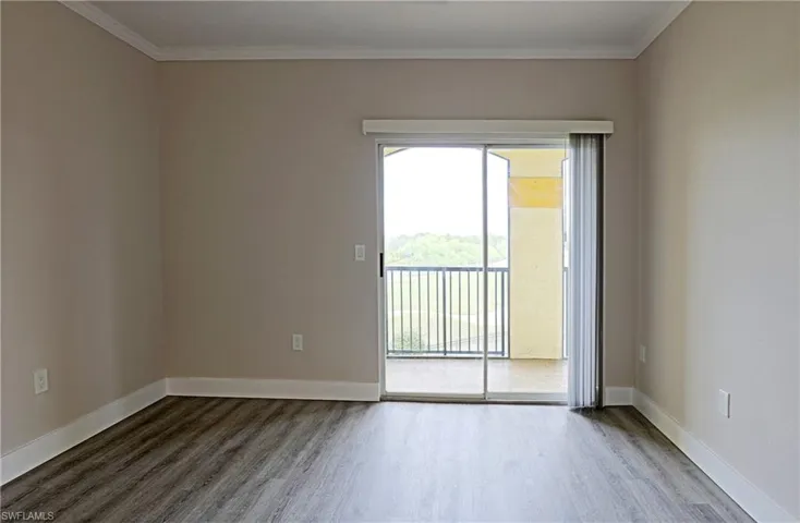 Empty room featuring wood finished floors and crown molding