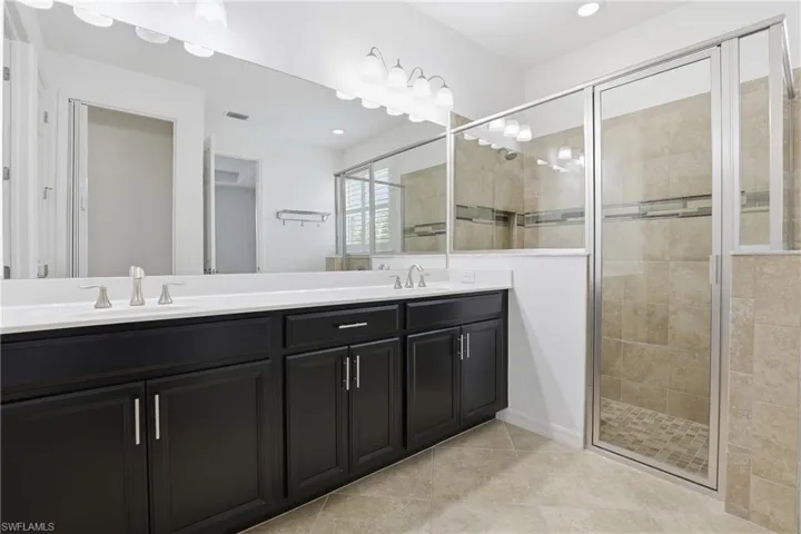 Full bathroom featuring double vanity, a shower stall, light tile patterned floors, and recessed lighting