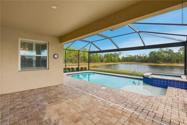 Relaxing pool / spa with a patio area, a sunroom, a lanai, a water view, and view of scattered trees
