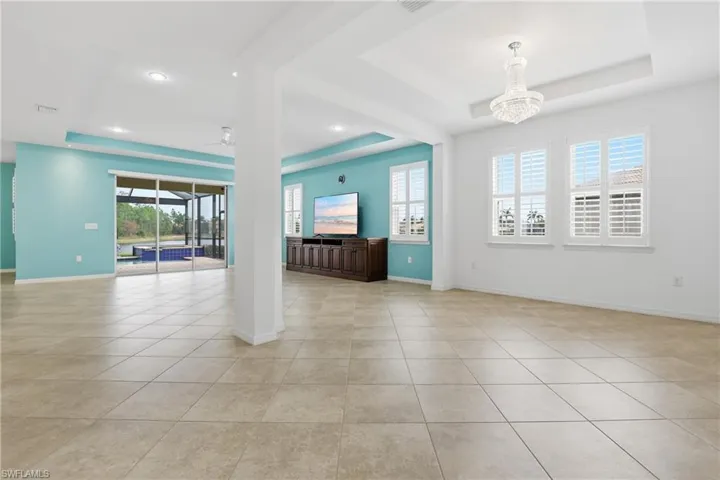 Unfurnished room with a raised ceiling, ceiling fan, a sunroom, and light tile patterned floors