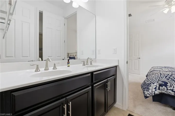 Bathroom with double vanity, a ceiling fan, light colored carpet, and ensuite bathroom