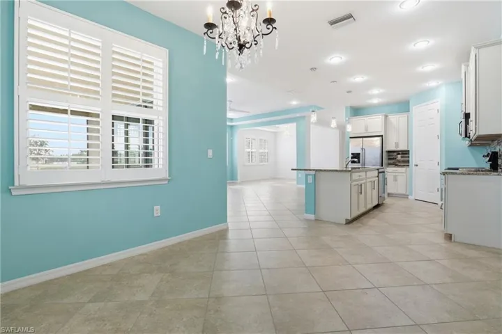 Kitchen with a chandelier, open floor plan, stainless steel appliances, and dark stone counters