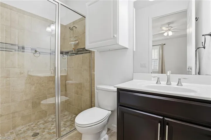 Full bath with a shower stall, vanity, and ceiling fan