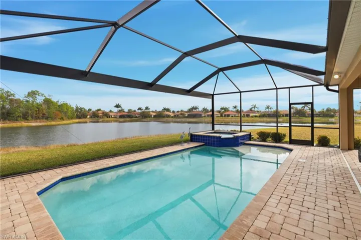 Integrated pool / spa featuring a sunroom, glass enclosure, a residential view, a lawn, and a patio
