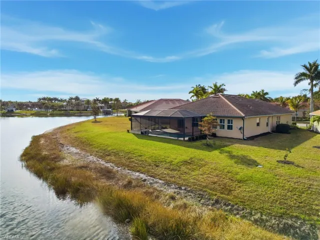 Rear view of property featuring a sunroom, glass enclosure, a water view, a lawn, and a pool