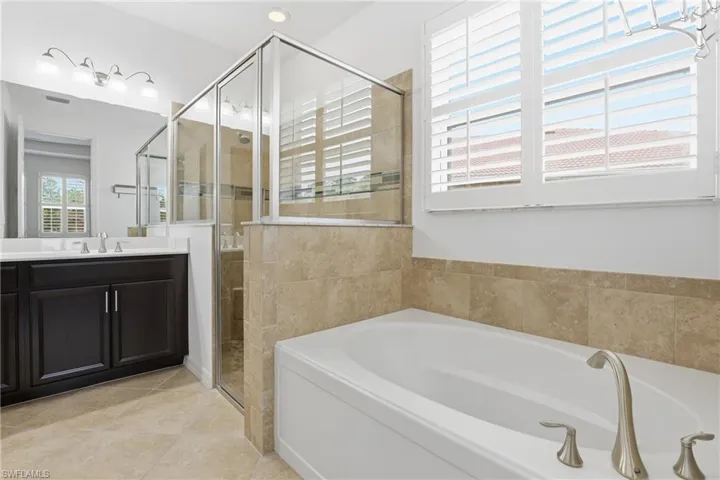 Bathroom with a garden tub, vanity, a shower stall, light tile patterned floors, and recessed lighting