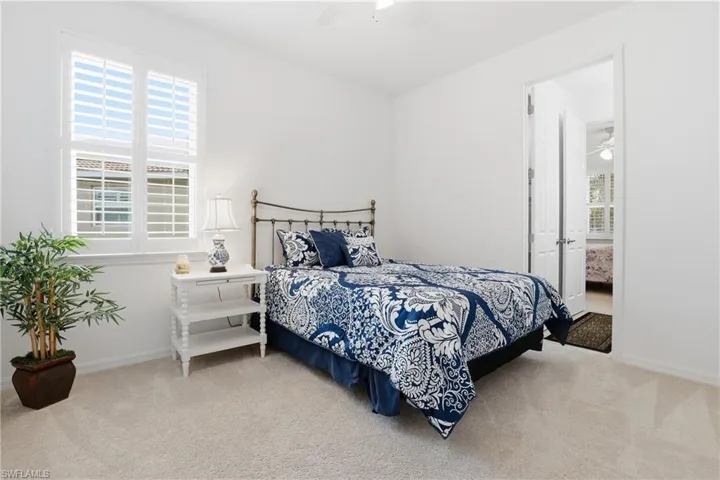 Bedroom featuring light carpet, a ceiling fan, and ensuite bath