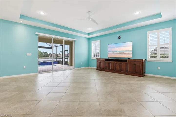 Empty room with ceiling fan, a raised ceiling, plenty of natural light, light tile patterned floors, and recessed lighting