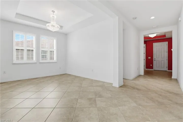 Empty room featuring hanging lights and a tray ceiling