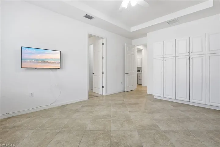 Unfurnished bedroom featuring a tray ceiling and a ceiling fan