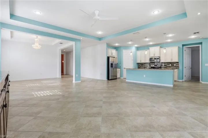 Unfurnished living room with a tray ceiling, a ceiling fan, and recessed lighting
