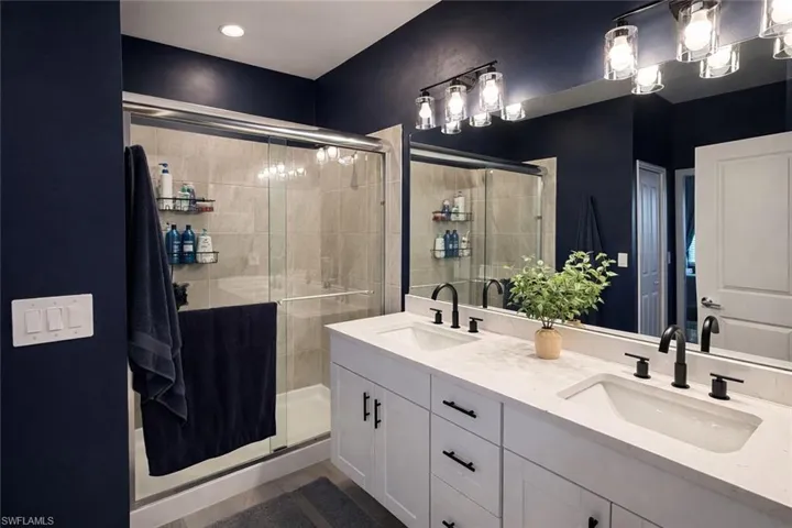 Bathroom featuring double vanity and a shower stall