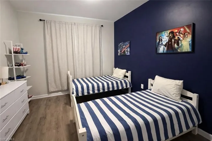 Bedroom featuring dark wood-type flooring and baseboards