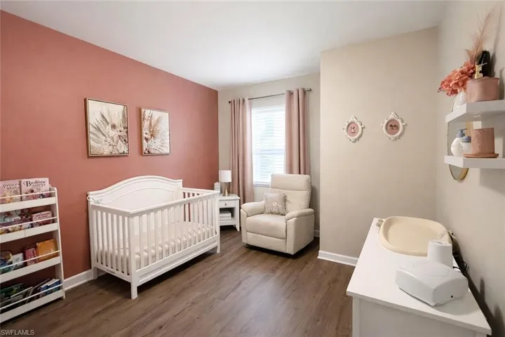 Bedroom featuring a crib and dark wood-type flooring
