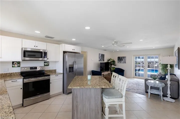 Kitchen featuring appliances with stainless steel finishes, white cabinets, open floor plan, light tile patterned floors, and recessed lighting