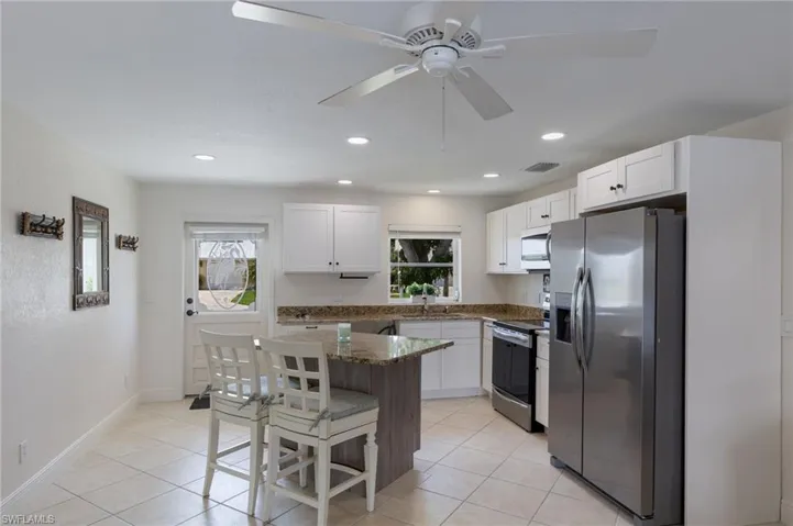 Kitchen with stainless steel appliances, white cabinets, a breakfast bar/center island, and light tile patterned floors
