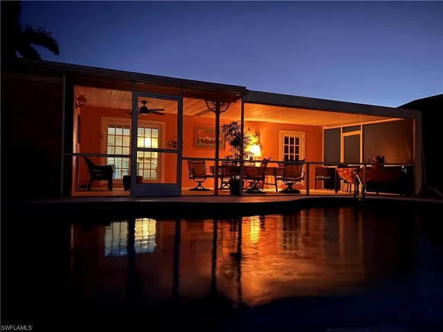 Back of house at twilight featuring an outdoor pool