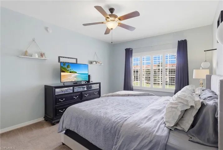 Spacious primary suite with plantation shutters and serene lake views.