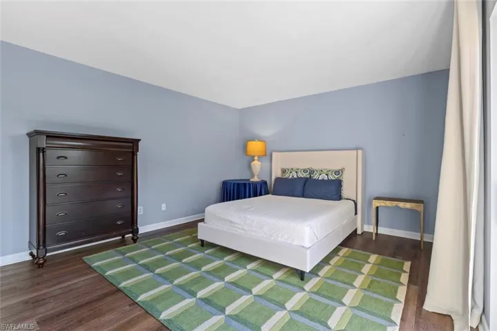 Bedroom with baseboards and dark wood-style flooring