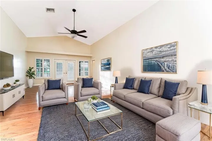 Living area with light wood finished floors, a ceiling fan, french doors, and high vaulted ceiling