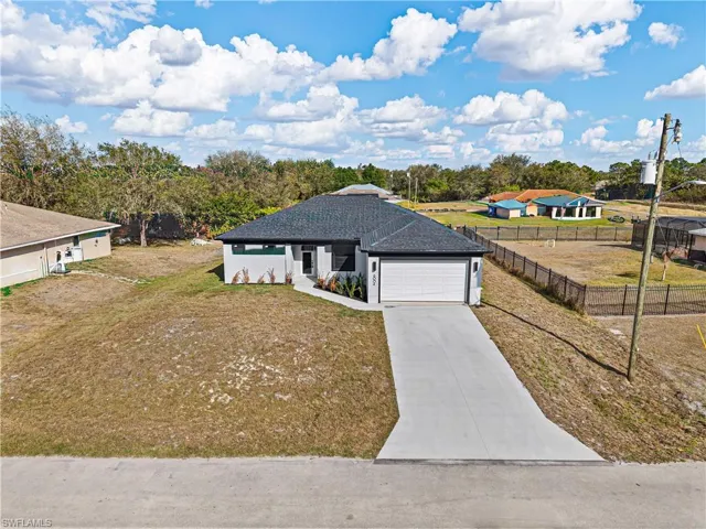 Ranch-style home with concrete driveway, roof with shingles, and a garage
