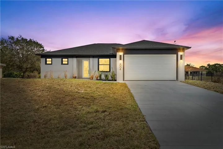 View of front of house featuring a front yard, concrete driveway, an attached garage, and stucco siding