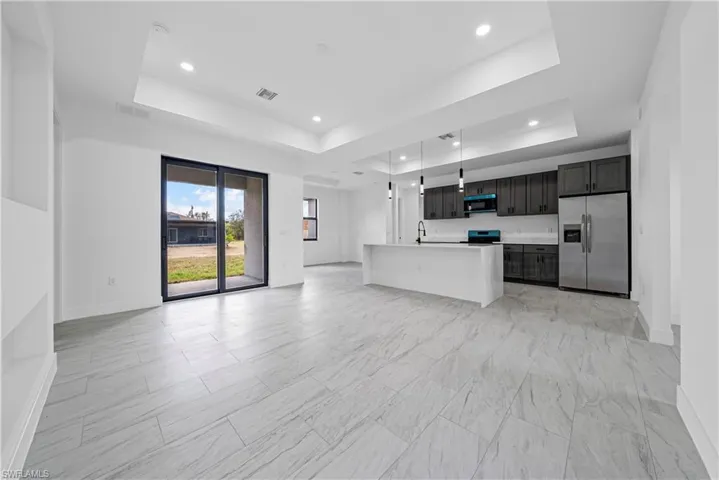 Unfurnished living room featuring a raised ceiling and recessed lighting
