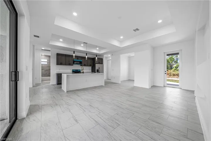 Unfurnished living room featuring a raised ceiling and recessed lighting