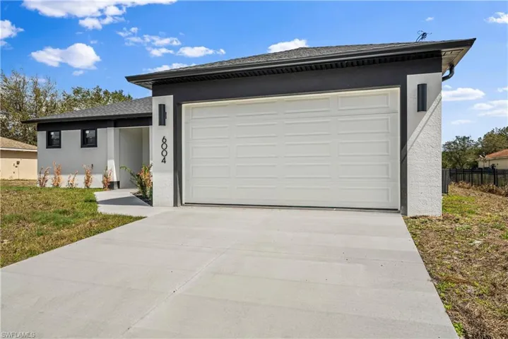 View of front of property with stucco siding, concrete driveway, a garage, and a shingled roof