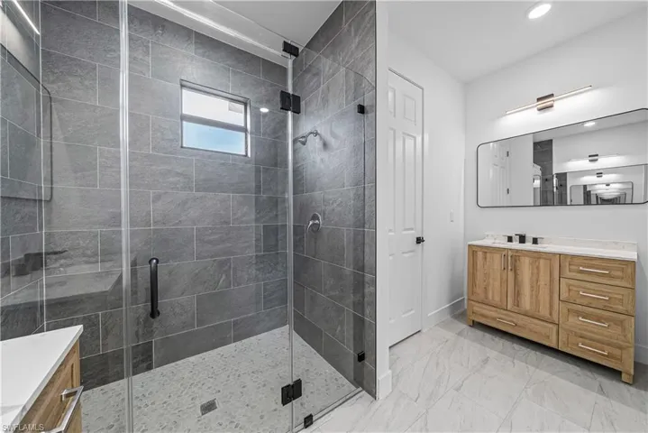 Full bathroom with vanity, a shower stall, and light marble finish floors