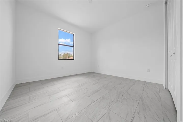 Empty room with vaulted ceiling and baseboards