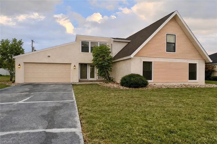 View of front of house featuring a front yard, driveway, stucco siding, and a garage
