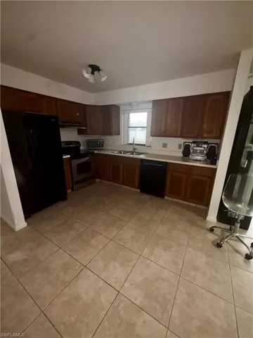 Kitchen with black appliances, light countertops, and light tile patterned floors