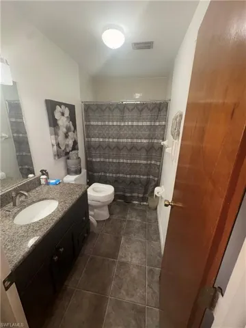 Bathroom with vanity, curtained shower, and dark tile patterned flooring