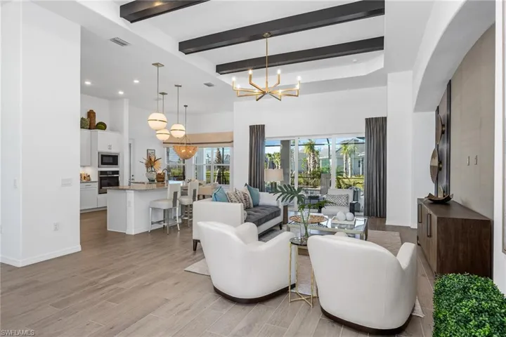 Living area with a chandelier, beam ceiling, light wood-style flooring, a high ceiling, and recessed lighting