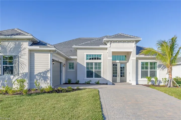 View of front facade with a garage, french doors, driveway, a front yard, and stucco siding