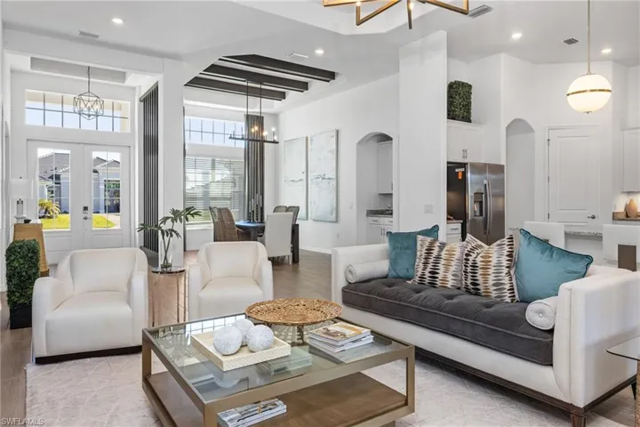 Living area featuring a chandelier, arched walkways, recessed lighting, light wood-type flooring, and a high ceiling