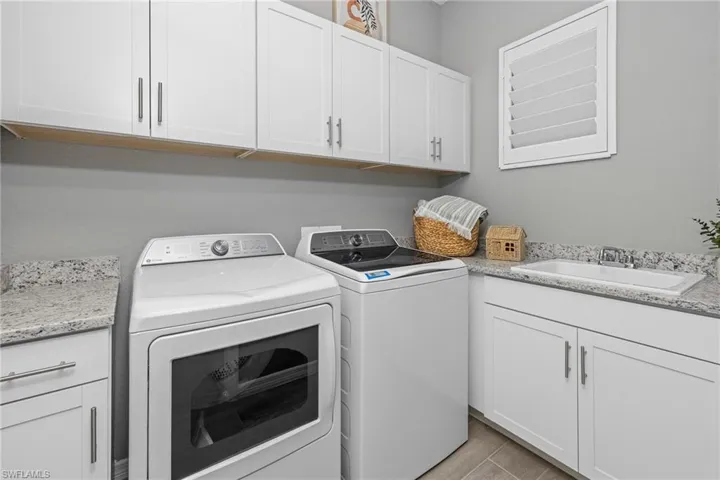Laundry room with washing machine and clothes dryer, cabinet space, and light wood-style flooring