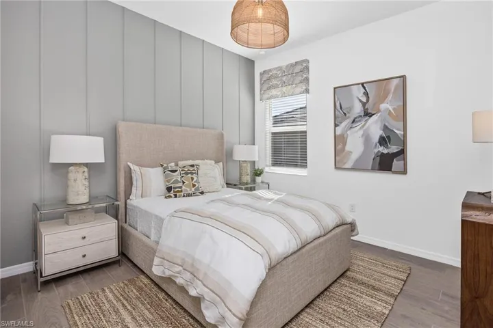 Bedroom with wood finished floors and a decorative wall