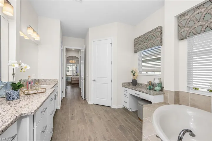 Ensuite bathroom with wood finished floors, a bath, and vanity