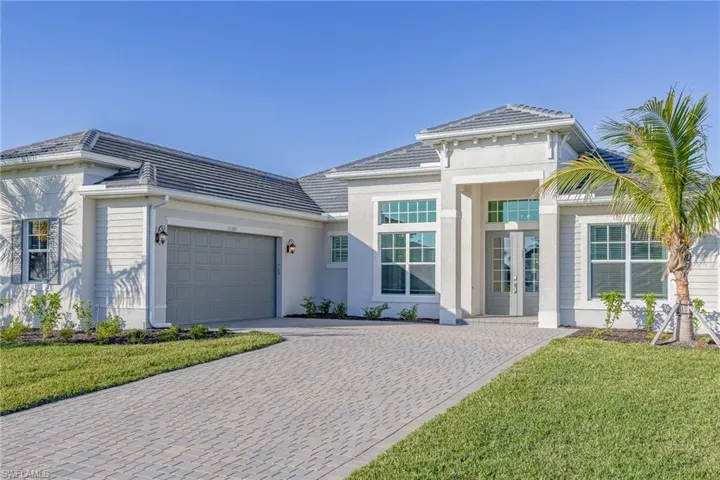 View of front of property with french doors, a garage, a front yard, and decorative driveway