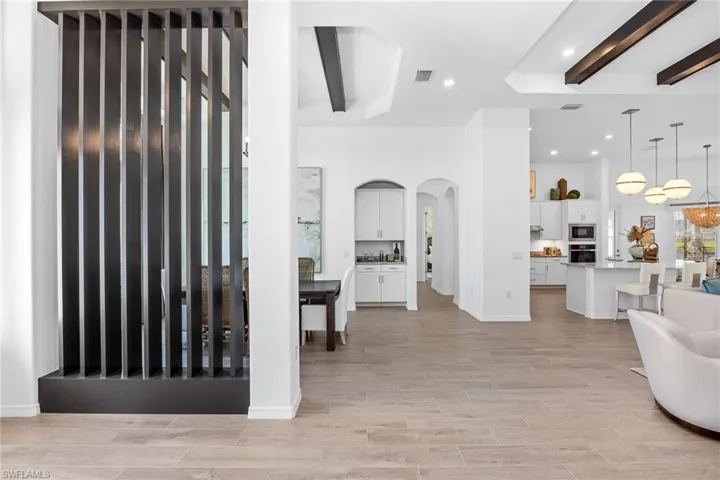 Foyer with beam ceiling, arched walkways, light wood-style flooring, recessed lighting, and a chandelier