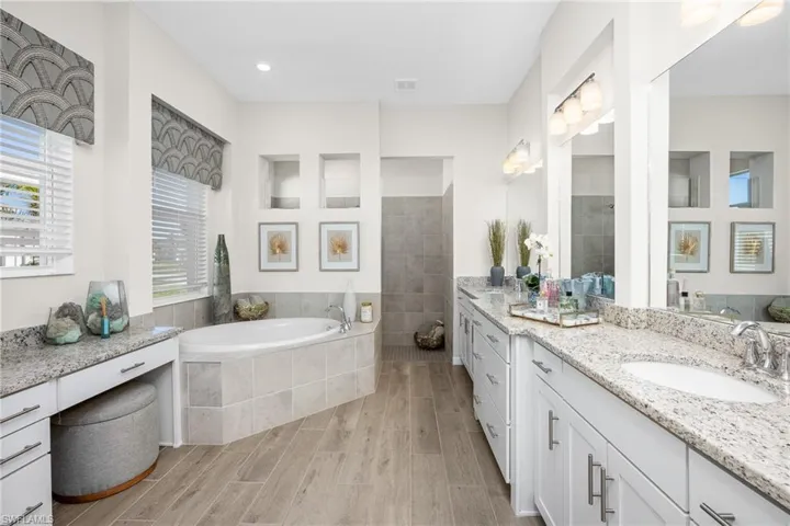 Full bath featuring vanity, wood finished floors, a garden tub, and tiled shower