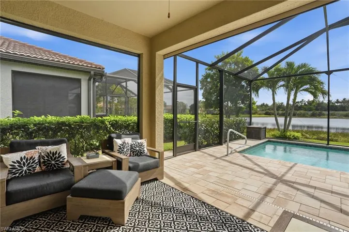 Outdoor pool featuring a sunroom, a patio, glass enclosure, and a water view