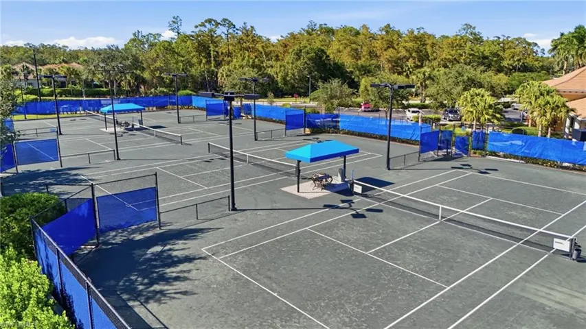 View of tennis court with view of scattered trees and community basketball court