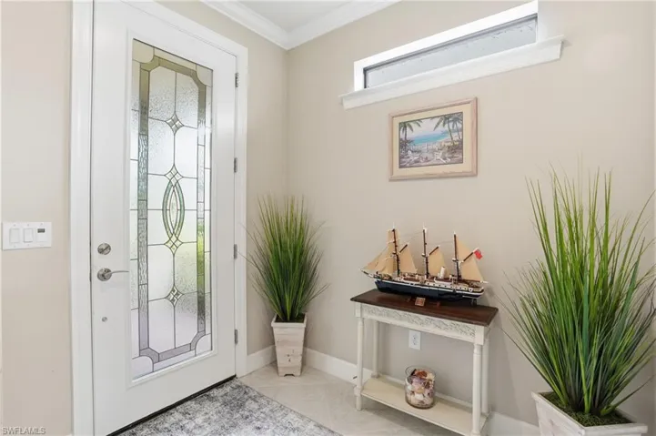 Foyer with tile patterned floors and crown molding