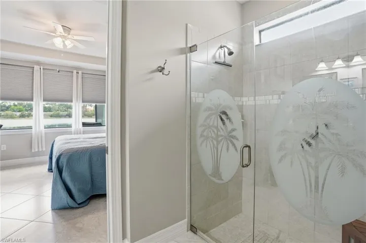 Ensuite bathroom with tile patterned floors, a stall shower, and a ceiling fan