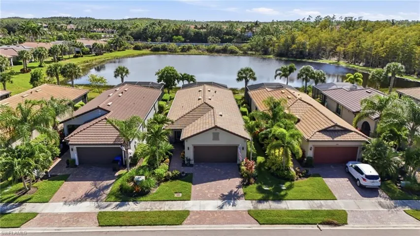 Aerial view of residential area with a nearby body of water and a tree filled landscape